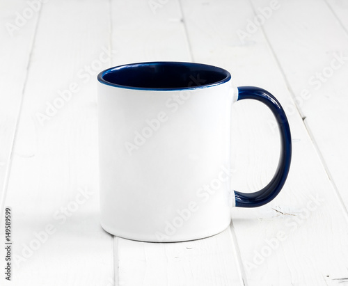 simple white cup with dark blue inside and handle on a planked table
