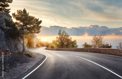 Asphalt road. Landscape with rocks, sunny sky with clouds and beautiful mountain road with a perfect asphalt at sunrise in summer. Vintage toning. Travel background. Highway in european mountains