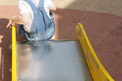 2 year-old boy playing on slider at playground