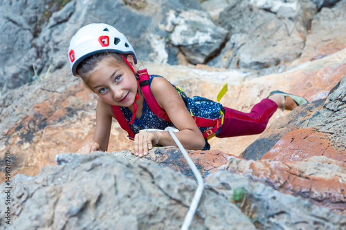 Little Child hanging of vertical Rock exercising extreme Sport