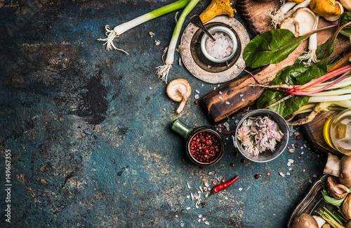 Fresh seasoning and vegetarian organic cooking ingredients for tasty cooking on dark rustic background, top view, place for text. Clean healthy organic vegan or vegetarian food concept