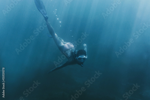 Freediver woman swimming in deep sea.
