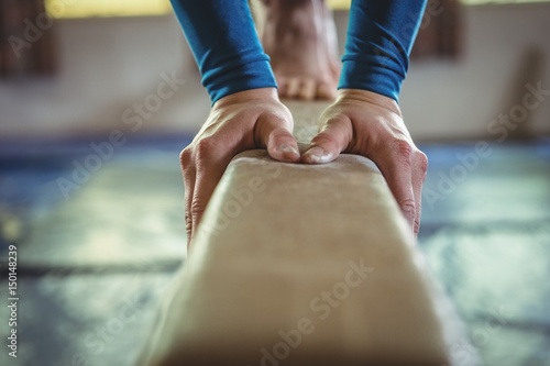 Female gymnast practicing gymnastics on the balance beam