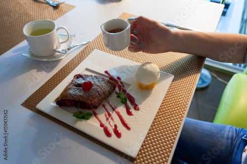 Десерт и кофе. Пирог, кружка кофе, рука, поднимающая кружку в ресторане и кафе.