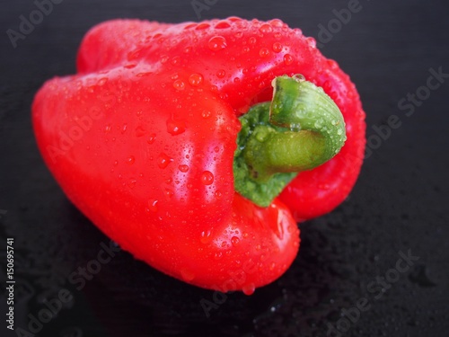 Red wet bell pepper on black background