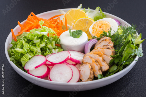 Mix of vegetables with saur cream sauce on a white plate. Raw vegetables and yogurt dressing in a white plate on wooden board.