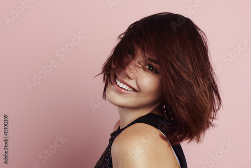 Beauty portrait of happy smiling female on pink background with copy space. 