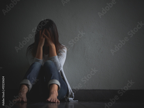 sad woman hug her knee and cry. Sad woman sitting alone in a empty room.