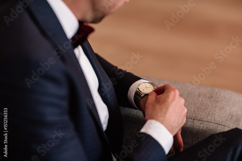 watch with white dial on the hand of a man in a white shirt
