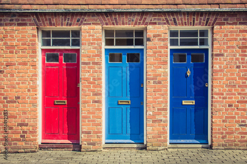 Three differently coloured front doors at the entrance of old English terraced houses. Canterbury, England.