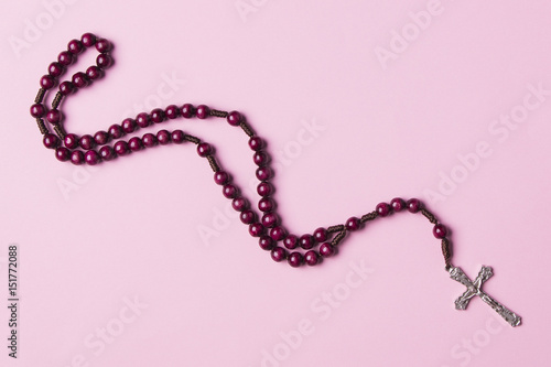 Rosary on a pink background. Christian cross.