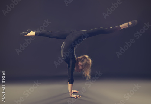 Young girl doing gymnastics on dark background