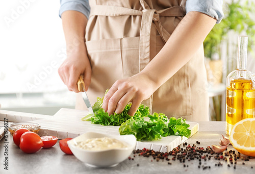 Woman cutting lettuce on kitchen table