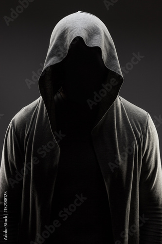 mysterious man in the hood with hidden face over dark grey background