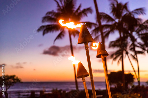 Hawaje zachód słońca z pochodniami ognia. Hawajska ikona, światła płonące o zmroku w nadmorskim kurorcie lub w restauracjach do oświetlenia i dekoracji na zewnątrz, przytulna atmosfera.