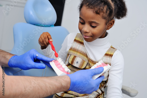 dentist shows a child how to properly American girl brushing teeth