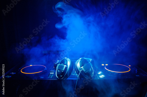 DJ Spinning, Mixing, and Scratching in a Night Club, Hands of dj tweak various track controls on dj's deck, strobe lights and fog, selective focus, close up. Dj Music club life concept