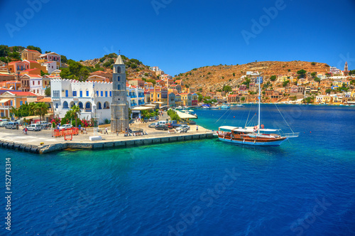 View on Greek sea Simy island harbor port, classical ship yachts, houses on island hills, tourists Aegean Sea bay. Greece islands holidays vacation travel tours from Rhodos island. Greece architecture