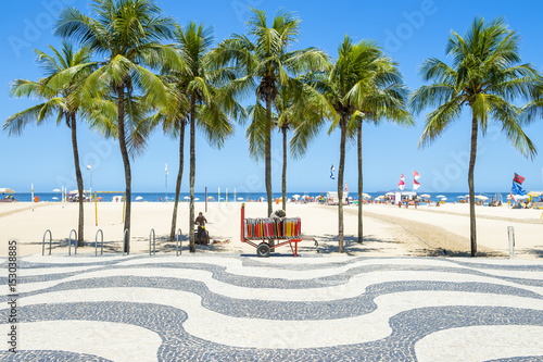Bright scenic view of Copacabana Beach with palm trees beside the iconic boardwalk in Rio de Janeiro, Brazil
