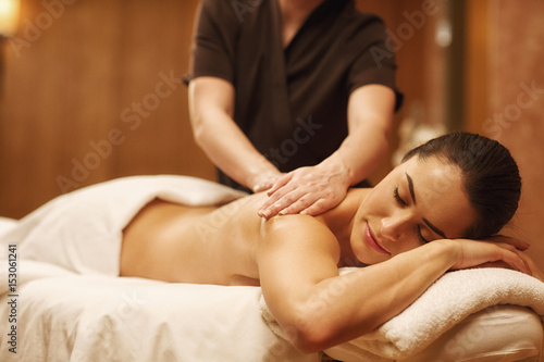 Beautiful woman relaxing receiving body massage at spa center