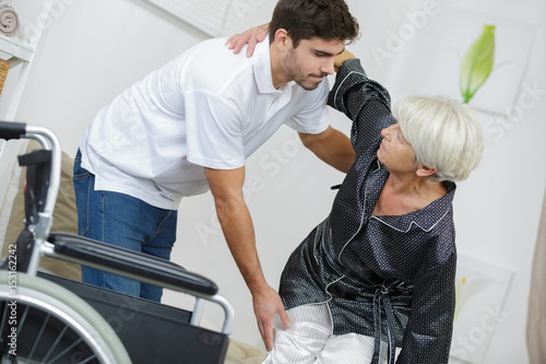 Man helping lady into wheelchair