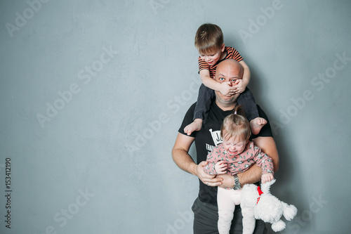 stressed young dad with two small children in his arms