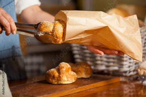 Mid-section of female staff packing sweet food in paper bag