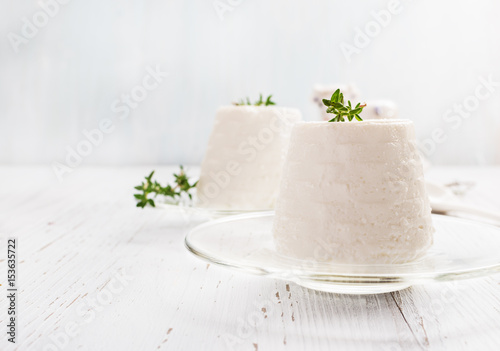 Italian ricotta cheese on glass plate on light background. Selective focus, free text space.