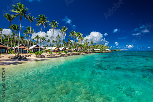 Tropical beach with with coconut palm trees and villas on Samoa