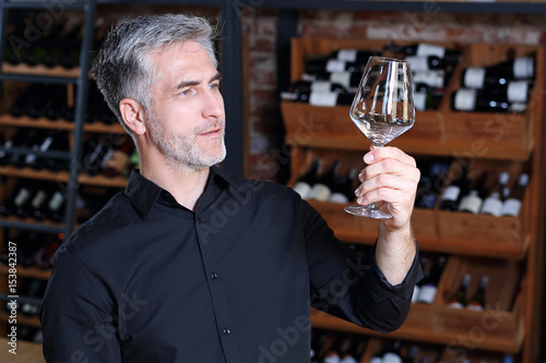 Kieliszek bez smug. Mężczyzna ogląda kryształowy kieliszek do wina.