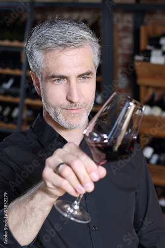 Przystojny mężczyzna ocenia barwę czerwonego wina.