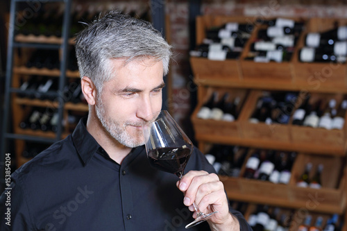 Winiarnia, mężczyzna degustuje czerwone wino.