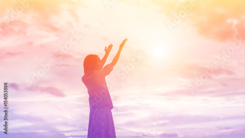 Silhouette of woman praying over beautiful sky background