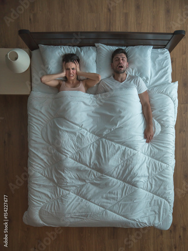 The man snore near the woman on the bed. view from above