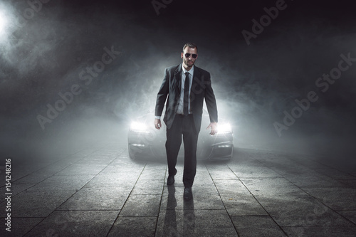 Mann im Anzug vor einem Auto in Dunkelheit