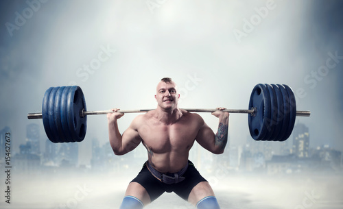 Muscular male weightlifter exercise with barbell