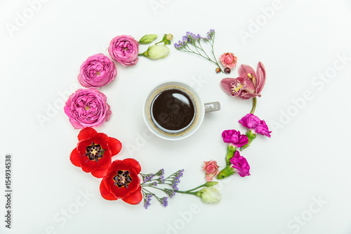 Top view of beautiful various blooming flowers around cup of coffee isolated on white