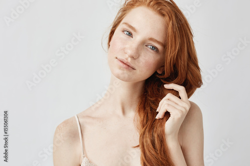 Portrait of tender beautiful girl with red hair smiling looking at camera.