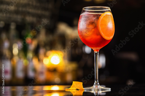 Closeup glass of spritz aperol cocktail decorated with orange at bright bar counter background.