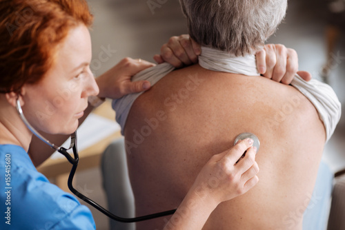 Learned focused therapist examining patients lungs