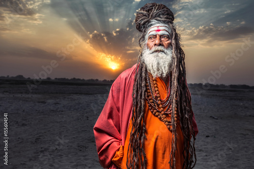 Portrait of sadhu standing with sunrise behind him, Varanasi, India.