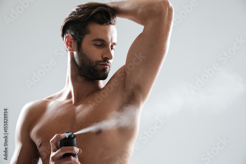 Horizntal image of young man using deodorant