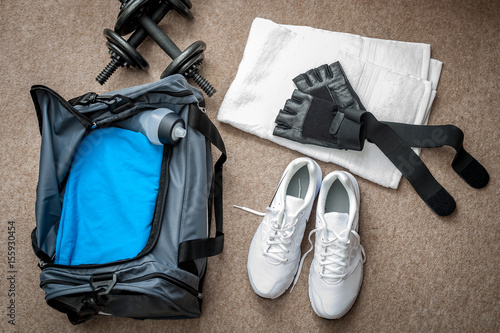Fitness equipment and working out concept with dumbbells, gym bag, white towel, running shoes, workout gloves and water bottle