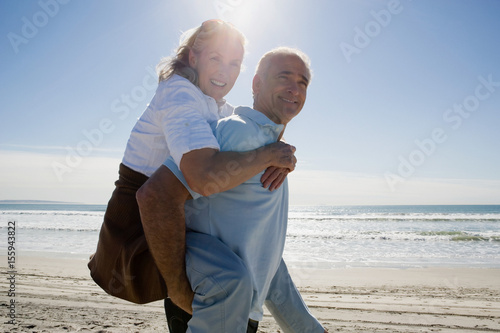 Senior man carrying woman on back