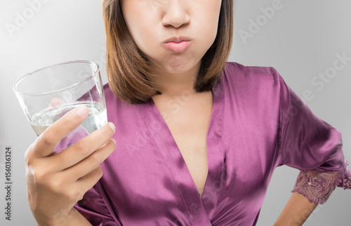 Woman rinsing and gargling while using mouthwash from a glass, During daily oral hygiene routine, Girl in a purple silk robe, Dental Healthcare Concepts