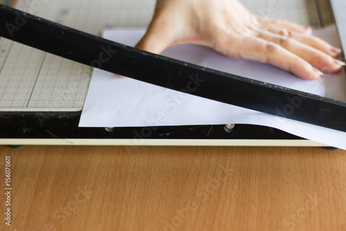 woman cutting paper with big paper cutter on table