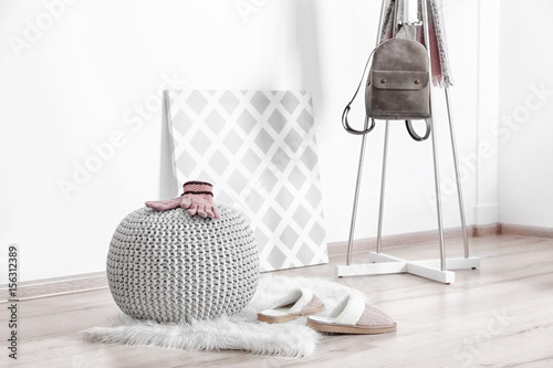 Knitted pouf with clothes in modern hall interior