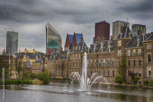 Binnenhof Palace of Parliament inThe Hague in The Netherlands before the Sunset. Against Dark Grey Clouds with Modern Skyscrapers on Background