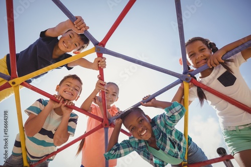 Portrait of happy schoolkids looking through dome climber