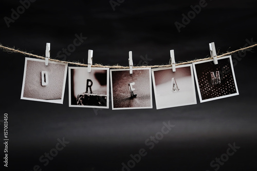 Rows of DREAM letters photo frames hanging with clothespins on dark background
